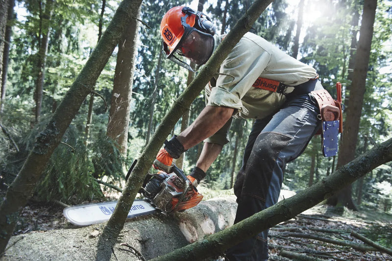 A HUSQVARNA 562XP-20 Chainsaw with an orange and gray body, ideal for forestry and gardens. The chainsaw features a long silver blade marked with "Husqvarna" and "X-Force." The machine has a sturdy handle and appears to be suited for heavy-duty cutting tasks.