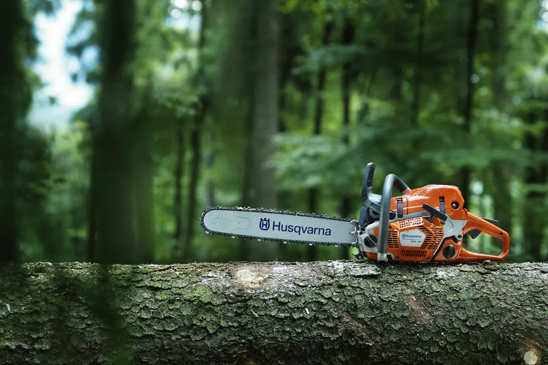 A HUSQVARNA 562XP-20 Chainsaw with an orange and gray body, ideal for forestry and gardens. The chainsaw features a long silver blade marked with "Husqvarna" and "X-Force." The machine has a sturdy handle and appears to be suited for heavy-duty cutting tasks.