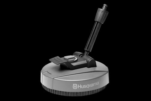 The Husqvarna Surface cleaner SC 300 is a circular, gray attachment featuring a rotating brush on the bottom and an adjustable black handle on top. Perfect for use with pressure washers, the brand name "Husqvarna" is printed on the side in white letters.