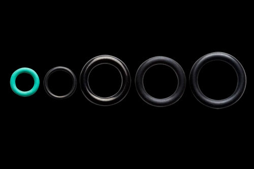 A row of five O-rings of varying sizes, with the smallest being green and the rest black, arranged neatly from smallest to largest against a black background. Ideal for those needing replacement O-rings in their Husqvarna Water Pressure O-Ring Kit by Husqvarna.