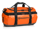 The Husqvarna Xplorer Duffel Bag 70L is an orange, sturdy tarpaulin bag featuring black handles, straps, and zippers. It showcases the Husqvarna logo in black on the front. Designed for convenience, it includes two top handles and an adjustable, removable shoulder strap.