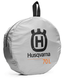 The Husqvarna Xplorer Duffel Bag 70L is an orange, sturdy tarpaulin bag featuring black handles, straps, and zippers. It showcases the Husqvarna logo in black on the front. Designed for convenience, it includes two top handles and an adjustable, removable shoulder strap.