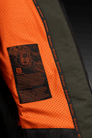 The Husqvarna Xplorer Shell Jacket - Forest Green is showcased on an invisible mannequin. Crafted from water-resistant shell material, this dark green jacket features a hood, zippered chest and side pockets, and eye-catching orange accents. It also proudly displays the Husqvarna logo stitched on both the chest and arm, while adjustable ventilation provides added comfort.