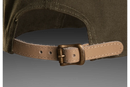 Introducing the Husqvarna Xplorer Cap in granite, featuring a tan leather patch on the front with a circular emblem displaying an "H" at its center. This cap boasts textured fabric and detailed stitching, promising a perfect fit thanks to its adjustable leather band at the back.
