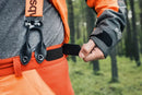 An image of Husqvarna Technical Extreme Waist trousers, high-visibility orange and black protective work pants with adjustable suspenders. These pants, made by Husqvarna, feature Cordura reinforcement at the knees and multiple pockets. The suspenders are adjustable and include reflective strips for enhanced visibility, making them ideal for forest work.
