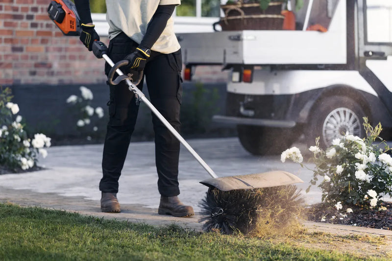 An orange and grey Husqvarna 525iLK Combi Trimmer (skin) with a long handle, a looped grip, and a protective cover on the cutting end. Ideal for maintaining gardens and lawns, this powerful trimmer features a battery pack at the back for cordless operation.