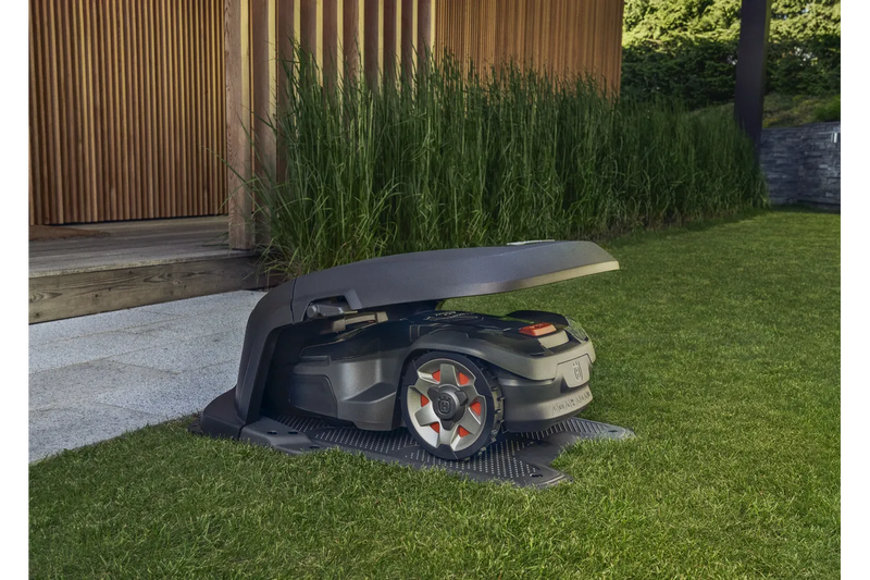 A gray Husqvarna branded attachment, likely a Husqvarna Aspire Automower® House - 320 NERA, 430X NERA, 450X NERA designed for a robotic lawn mower. Perfect for maintaining lawns and gardens, the attachment features a streamlined design with mounting points for secure installation.