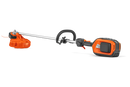 Image of an orange and black Husqvarna 525iLXT Battery Grass Trimmer (skin) perfect for gardens. The trimmer features a long straight shaft with a cutting head at one end and a battery pack at the other. There is a circular handle midway along the shaft for better grip and control, reminiscent of Husqvarna's ergonomic design.