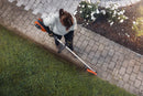 An orange and grey Husqvarna 525iLK Combi Trimmer (skin) with a long handle, a looped grip, and a protective cover on the cutting end. Ideal for maintaining gardens and lawns, this powerful trimmer features a battery pack at the back for cordless operation.