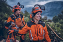 Displayed is the "Husqvarna Extreme Forest Jacket," an orange and black outdoor jacket with gray accents and reflective strips. It features a high collar, long sleeves, ventilation openings for added comfort, and zippered pockets. The brand name "Husqvarna" is visible on the chest.
