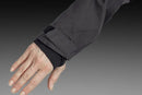 The Husqvarna Xplorer Shell Jacket Charcoal Black - Women by Husqvarna is a dark gray, hooded outdoor jacket. This windproof jacket features a full front zipper, zippered pockets, and subtle branding on the chest. It has long sleeves, adjustable ventilation, and a slightly fitted design, making it suitable for various weather conditions.