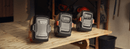 The Husqvarna 40-C80 Battery Charger, in gray, features an attached cable and a slot for the battery, prominently displaying the Husqvarna logo on the front. Designed for efficient charging, this compact single bay charger boasts an angled design, making it ideal for portable use.
