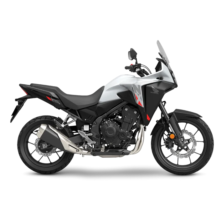The Honda NX500, a sleek and modern motorcycle by Honda, showcases a silver and black color scheme with programmed fuel injection. It features a prominent windshield, angular design elements, and alloy wheels. The side profile accentuates its sporty and aerodynamic build.