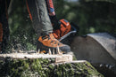 A pair of orange and black Husqvarna Protective leather boots with saw protection - Technical 24 with rugged soles. The boots feature red and black laces, a reinforced toe area, and detailed stitching. One boot stands upright while the other is tilted to show its tread pattern, making them perfect motorcycle accessories for adventurous rides.