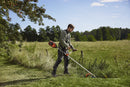 A Husqvarna 325iR Brushcutter (skin) lays on a white background. Perfect for lawns and other outdoor maintenance, the tool features a long silver shaft with a black handle at the top and an orange cutting head at the bottom. The motor is housed in an orange casing near the handle.