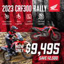 The Honda CRF300 Rally is a red and black adventure motorcycle with a windscreen, off-road tires, and blue & white accents. Designed for rugged terrain, it is highlighted on a plain white background, showcasing its sleek design and impressive off-road performance.