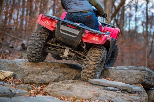 The Honda TRX700FA5 is a red and black all-terrain vehicle (ATV) built for off-road adventures. Featuring rugged tires and a sturdy build, it includes a four-wheel-drive system as well as front and rear cargo racks, blending sleek design with adventure-ready capability.