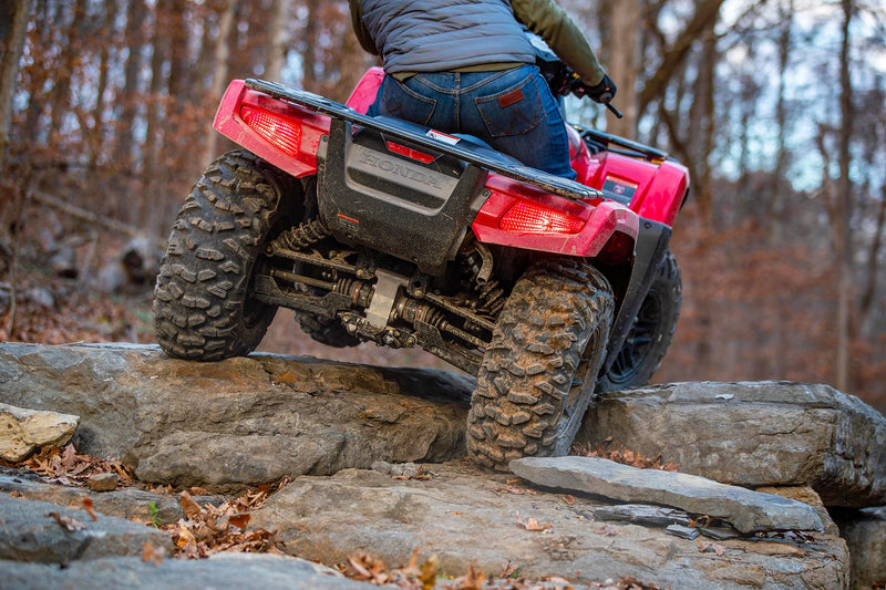The Honda TRX700FA5 is a red and black all-terrain vehicle (ATV) built for off-road adventures. Featuring rugged tires and a sturdy build, it includes a four-wheel-drive system as well as front and rear cargo racks, blending sleek design with adventure-ready capability.