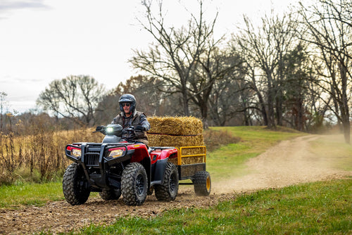 The Honda TRX700FA5 is a red and black all-terrain vehicle (ATV) built for off-road adventures. Featuring rugged tires and a sturdy build, it includes a four-wheel-drive system as well as front and rear cargo racks, blending sleek design with adventure-ready capability.