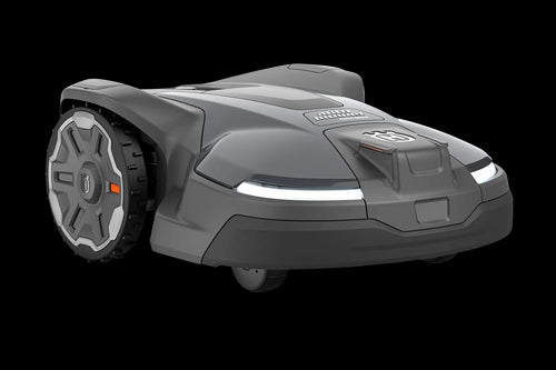 The Husqvarna Automower 430X NERA is a sleek, grey robotic lawn mower featuring two large wheels at the rear and two smaller wheels at the front. It boasts a red stop button on top, LED headlights, and proudly displays the Husqvarna logo on the front. With its modern design, this mower is equipped with object avoidance technology and can be conveniently controlled via the Automower Connect app.