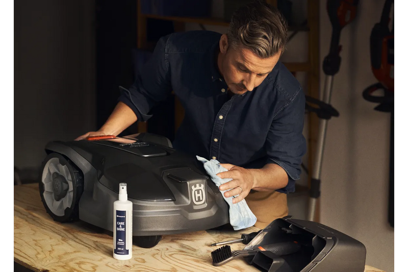 Introducing the Husqvarna Automower Cleaning and Maintenance Kit: This all-inclusive set comes complete with a plastic container, grey dustpan, blue cloth, cleaning spray bottle, handheld brush, small white block, scraper tool, and screwdriver. Perfect for maintaining your Husqvarna automower with ease and keeping it in top condition.