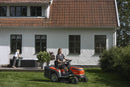 The Husqvarna Battery TC 100i Tractor in bright orange and black features a steering wheel, comfortable seat, efficient collecting system, and durable tires. It boasts sleek lines and a modern design for dynamic mowing.