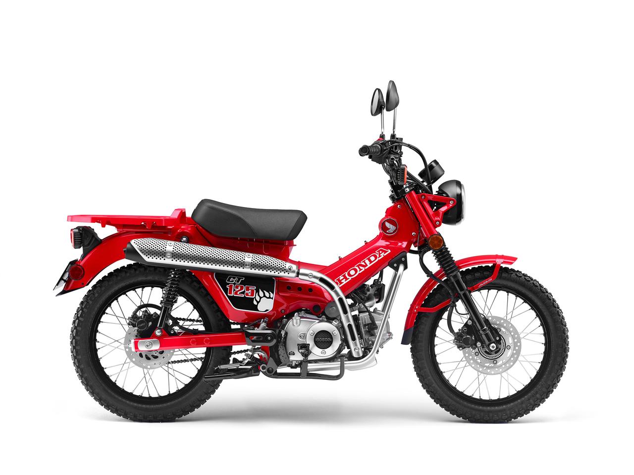 A Honda CT125 Trail & Farm motorcycle is displayed on a white background. It features a rugged design with off-road tires, an elevated exhaust pipe, and a rear cargo rack. The bike has a compact, utilitarian look with its 125cc engine, designed for both urban and rough terrain rides.