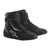 The Alpinestars Fastback V2 DS Riding Shoes by ALPINESTARS are black high-top racing shoes with a sleek design and white star logo, featuring waterproof and breathable DRYSTAR® technology. They include laces, an extra strap for fastening, and a textured sole for road riding grip.