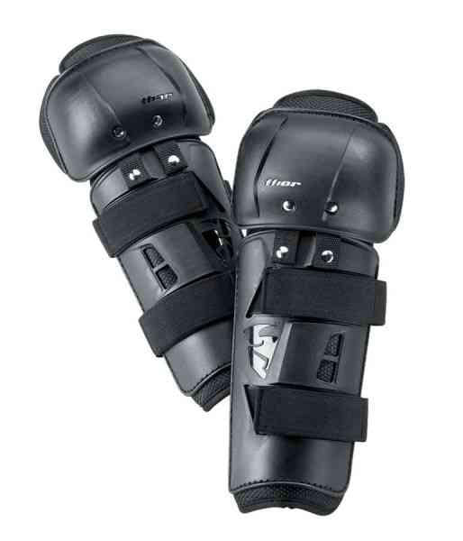 A pair of black KNEEGUARD S24 THOR MX SECTOR ADULT shin guards with reinforced knee and shin panels. These Thor MX kneeguards feature adjustable velcro straps and small ventilation slots for breathability. The THOR MX brand logo appears on both the shin and knee areas, adding to the sleek and protective design.
