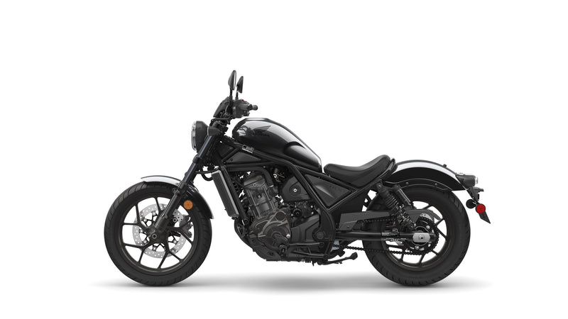 A black Honda Rebel CMX1100 DCT motorcycle is shown in profile against a white background. The cruiser class bike features a low seat, wide handlebars, and a robust engine with automatic transmission. It boasts a modern, minimalist design with sleek lines and a matte finish, including spoked wheels and disc brakes.