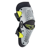 The Alpinestars SX-1 Youth Knee Guards by Crown Kiwi Enterprises Limited are designed in black and gray with yellow highlights and a perforated pattern. They feature adjustable straps, a branded logo, and a dual pivot hinge system to improve knee injury prevention.