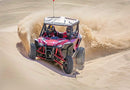 A red Honda Talon R off-road vehicle is pictured. It features robust, large tires, a roll cage, and sporty accents. The vehicle has a rugged design suitable for rough terrain, with visible shock absorbers and a roof for protection—perfect for sport side-by-side enthusiasts.