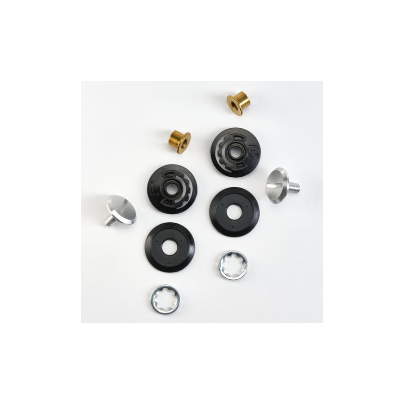 A collection of small mechanical components for the REPLACEMENT BASE PLATE ELDORADO E70 arranged on a white surface. The Eldorado E70 components include black and silver washers, brass cylindrical bushings, and silver screw-like parts with ring-shaped objects.