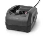 A black Husqvarna QC250 Battery Charger with a compact, ergonomic design. Ideal for forestry and gardens, the charger features a visible charging slot and a cable extending from the back. The brand name "Husqvarna" is prominently displayed on the front against a transparent background.