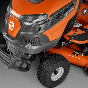 A Husqvarna TS242TXD Ride-On Mower is shown in bright orange, featuring a comfortable gray seat with armrests, large textured tires, and a robust ClearCut™ deck underneath. The side discharge tractor boasts a modern design with the prominent Husqvarna logo on its front.