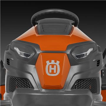 A Husqvarna TS242TXD Ride-On Mower is shown in bright orange, featuring a comfortable gray seat with armrests, large textured tires, and a robust ClearCut™ deck underneath. The side discharge tractor boasts a modern design with the prominent Husqvarna logo on its front.