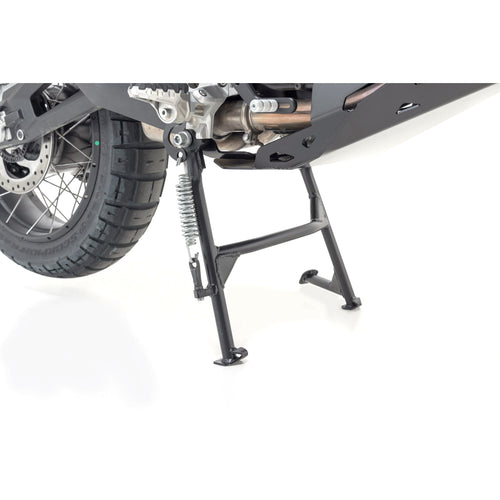 Close-up of the SW MOTECH Centre Stand for Ducati Desert X 23-on against a white background. It showcases components such as part of the rear wheel, suspension, and exhaust system, crucial for motorcycle maintenance. The stand is extended, securely supporting the bike.