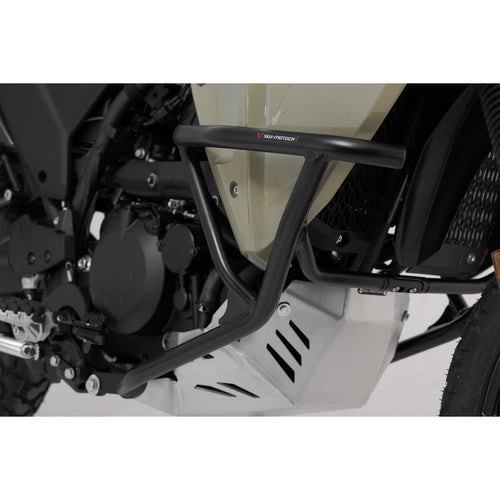 A close-up view of a Kawasaki KLR650 motorcycle featuring the CRASH BARS SW MOTECH KAWASAKI KLR650 22-23 by SW MOTECH. The image captures the front and side profile, showcasing the bike's beige and black color scheme, rugged tires, front suspension, engine guard, SW-MOTECH crash bars, and rear luggage rack against a plain white background.
