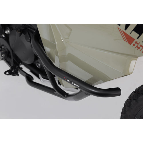 A close-up view of a Kawasaki KLR650 motorcycle featuring the CRASH BARS SW MOTECH KAWASAKI KLR650 22-23 by SW MOTECH. The image captures the front and side profile, showcasing the bike's beige and black color scheme, rugged tires, front suspension, engine guard, SW-MOTECH crash bars, and rear luggage rack against a plain white background.