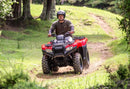 Farmer safely riding his TRX420 through farm trails wearing a helmet 