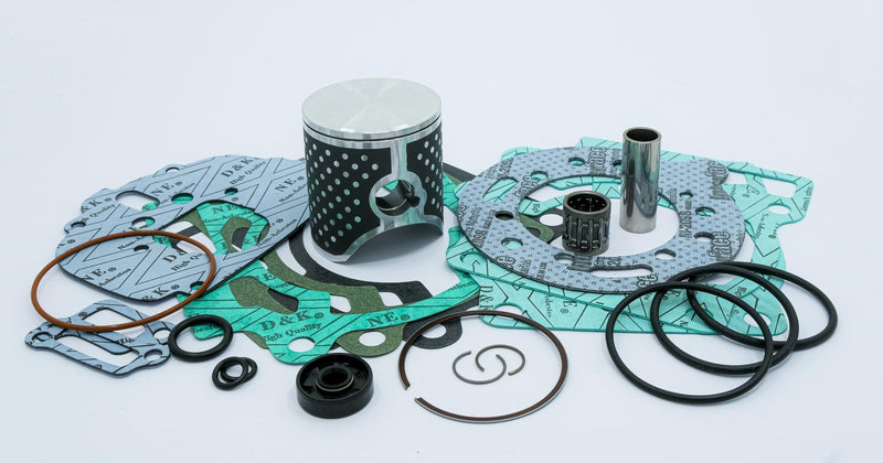 A variety of engine components arranged on a white background, including a TOP END KIT VERTEX RACE EVOLUTION YZ125 YZ125X 05-21 53.95MM by VERTEX, gaskets, O-rings, a cylindrical pin, and various seals and bearings. The gaskets are distinguishable by their light blue and green color with printed text.