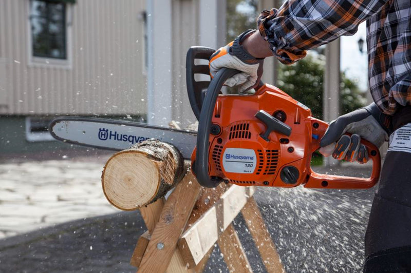 A Husqvarna 120 Mark II Chainsaw with an orange body and a silver blade is shown. The word "Husqvarna" is printed on the side of the blade. Positioned at a slight angle, it highlights its ergonomic handle and design, making it perfect for maintaining lawns and garden tasks efficiently.