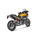 The Akrapovic Slip On BMW F900R/XR 2020-23 exhaust boasts a sleek metallic design with a rectangular carbon fiber-trimmed end, featuring a red logo on its black segment. Set diagonally against a white backdrop, it beautifully captures the signature AKRAPOVIC sound.